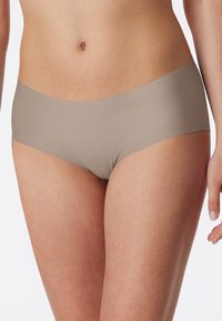 Beige shortsit, joissa on sileä pinta ja hipster-muotoilu, jossa on saumatonta vyötärönauhaa ja ei näkyviä ompeleita minimalistista ilmettä varten.