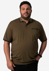 Zelená polokošile s krátkým rukávem, kapsou a černým lemem na límci a rukávech, vyrobená z měkké, strukturované tkaniny.
