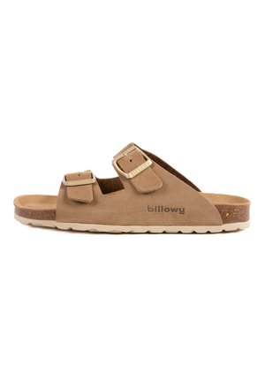 Sandales en suede marron avec deux boucles réglables, une semelle en liège et une semelle extérieure en caoutchouc texturé avec un motif ondulé. Nom de la marque visible.