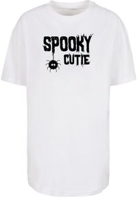 Balts kokvilnas T-krekls ar tekstu "SPOOKY CUTIE" treknajās melnās burtos. Karikatūras zirneklis karājas no burta "O".