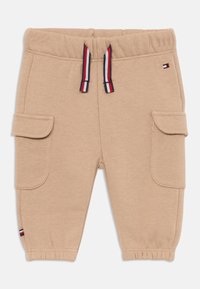 Pantalones joggers de algodón beige con cintura elástica, cordón en rojo, blanco y azul, y dos bolsillos laterales. Puño en el tobillo.