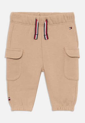 Bež pamuk od jogger hlača s elastičnim pojasom, vezicom u crvenoj, bijeloj i plavoj boji, te dva bočna džepa. Manžetna na gležnju.