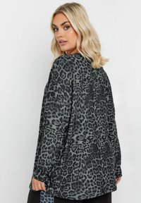 Haut oversize gris à imprimé léopard avec des manches longues, en tissu doux, à col rond et à ourlet incurvé. Présente une silhouette décontractée.