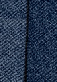Tejido de mezclilla en tonos azul oscuro y azul claro, que muestra una textura suave con un sutil patrón de tejido diagonal. Suave al tacto.