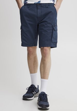 Marineblå cargo shorts med flere lommer, lavet af letvægtsstof. Har en afslappet pasform og knælængde design, parret med hvide sokker og sko.