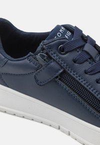 Sneaker in pelle blu navy con lacci, cerniera laterale e suola in gomma bianca. Presenta dettagli cuciti e una cucitura testurizzata.