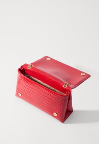 Clutch in pelle rossa con texture a coccodrillo, dotato di chiusure magnetiche dorate, apertura a ribalta e rivestimento interno beige visibile su sfondo bianco.