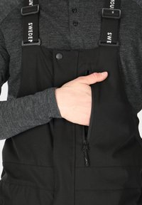 Black waterproof overalls with adjustable straps, featuring a zippered chest pocket and a smooth fabric texture.