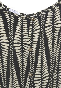 Black fabric top featuring white fern leaf patterns, with a round neckline and gold button details along the front.