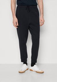 Marina joggerbyxor i mjukt tyg med elastisk midja och muddar vid anklarna. Kombinationen med vita sneakers med gummisula.