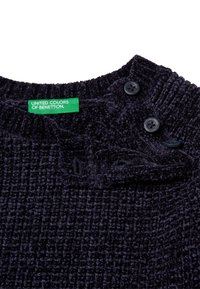 Černá texturovaná pletenina s трех černými knoflíky na límci a zeleným štítkem "United Colors of Benetton".