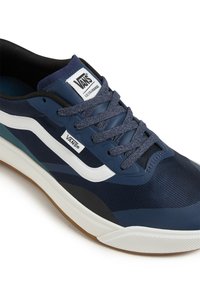 Námořnické modré sportovní boty s síťovinovým svrškem, bílým bočním pruhem, zaoblenou špičkou a gumovou podešví. Obsahují šedé tkaničky a polstrovaný límec.