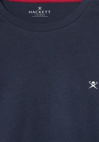 Tamno plava pamučna majica s okruglim izrezom, s crvenim detaljima na ovratniku i malim bijelim logotipom na lijevoj strani koji prikazuje ukrštene predmete.