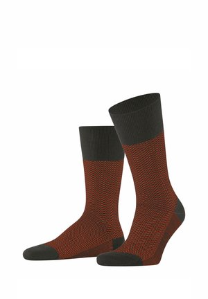 Chaussettes à motif chevron en orange et gris foncé. Elles présentent un bord-côtes et un bout renforcé, conçus pour le confort et la durabilité.