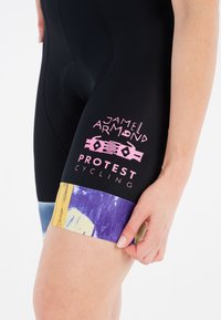 Zwarte fietsshorts met een gevoerd zitvlak, met roze en paarse grafische accenten bij de zoom en merktext op de zijkant.