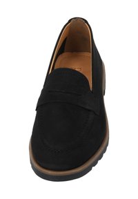 Mocassino in suede nero con un design cucito, suola piatta in gomma e una piccola fascia decorativa sul collo del piede. L'interno presenta una fodera color beige.
