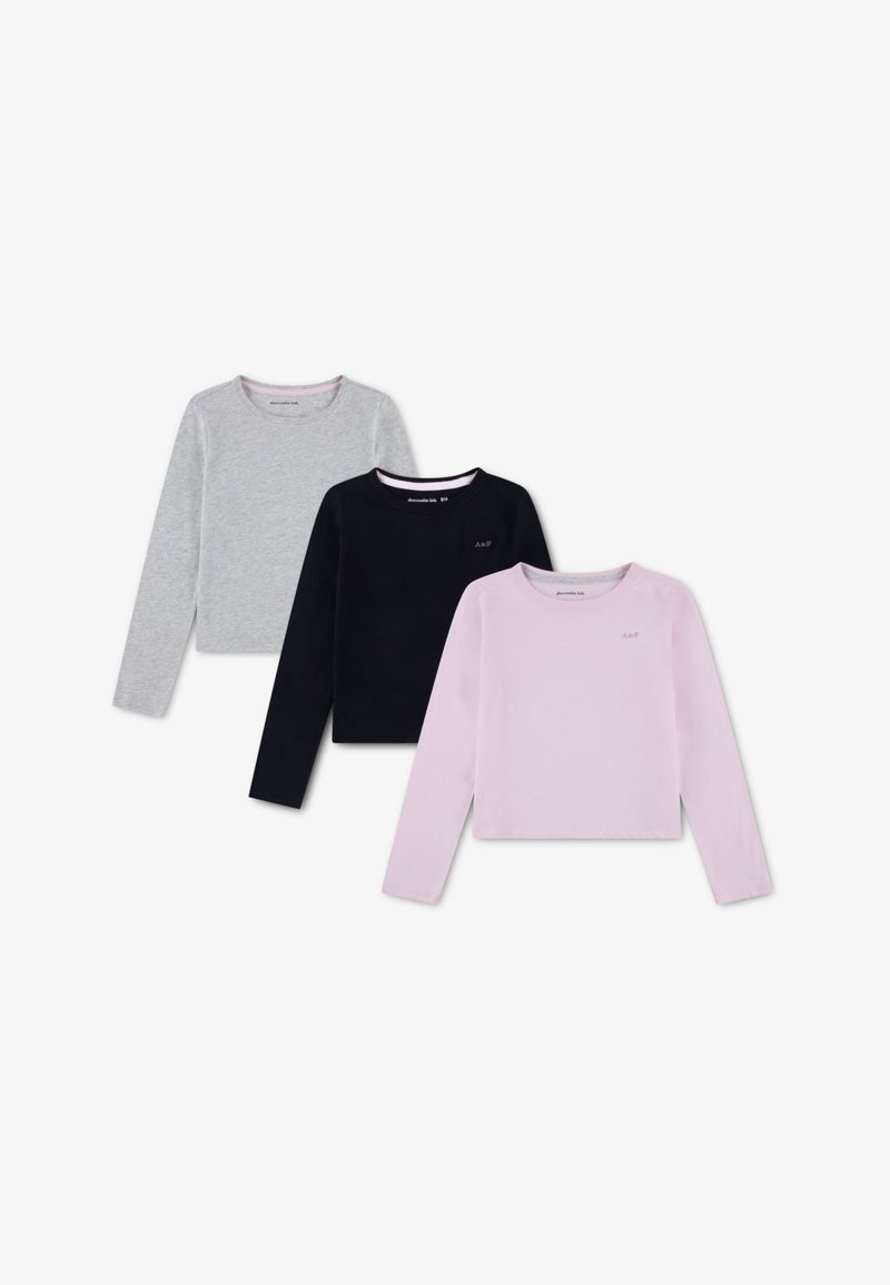 Ensemble de trois chemises à manches longues en coton gris, noir et rose. Chacune présente un col rond et une coupe ajustée avec un branding minimal.