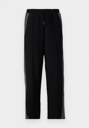 Pantalones de chándal negros con paneles laterales grises, que cuentan con una cintura elástica con cordón, una textura suave y un diseño de pierna ajustada.