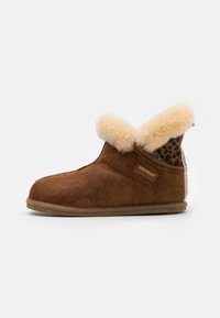 Brown sheepskin slipper featuring a faux fur cuff, suede exterior, a padded interior, and a textured sole with a leopard print back panel.