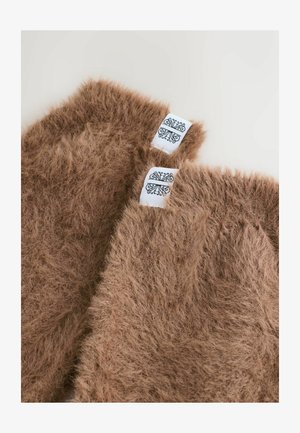 Ciorapi de iarnă din blană faux maro, cu o textură moale, având etichete albe decorate cu un modeli negru.