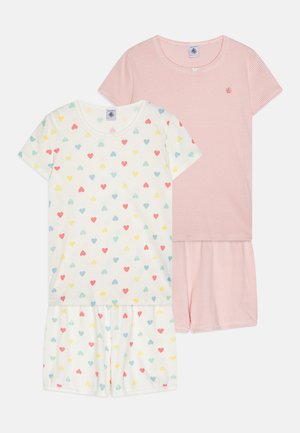 Två set barnpyjamas; det ena har en vit bas med flerfärgade hjärtan, det andra är rosa med vita ränder. Kort ärm och shorts.