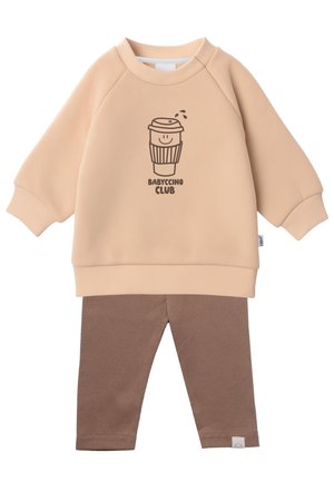 Pfirsichfarbener Sweatshirt mit einem Cartoon-Kaffeetassen-Design, kombiniert mit braunen Rippleggings. Weicher Stoff, lässige Passform und gerippte Bündchen.