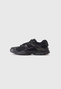 Chaussure de sport noire avec un mélange de matériaux en mesh et synthétiques, présentant une surface texturée et une semelle avec un rembourrage accentué.