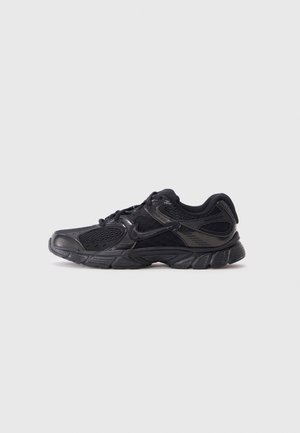 Chaussure de sport noire avec un mélange de matériaux en mesh et synthétiques, présentant une surface texturée et une semelle avec un rembourrage accentué.