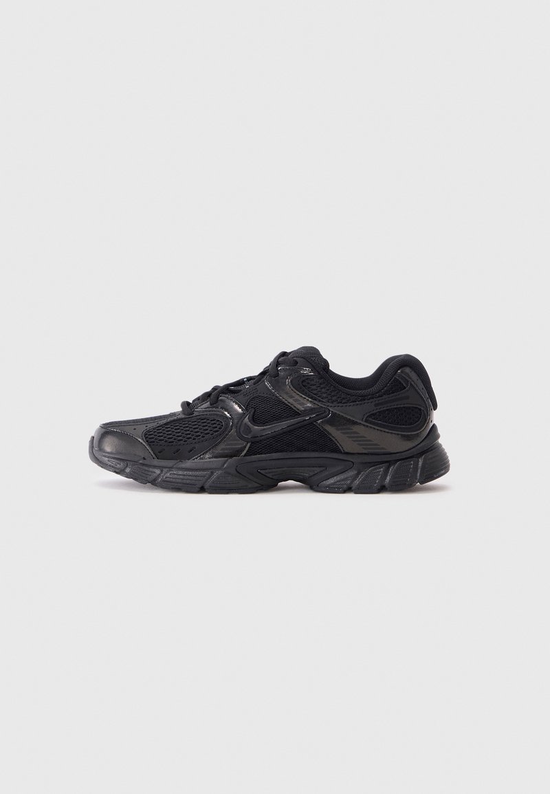Chaussure de sport noire avec un mélange de matériaux en mesh et synthétiques, présentant une surface texturée et une semelle avec un rembourrage accentué.