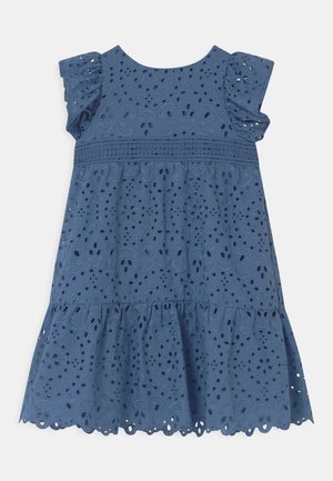 Robe en tissu ajouré bleu avec manches courtes à volants, jupe à étages, motifs découpés complexes et ourlet festonné.