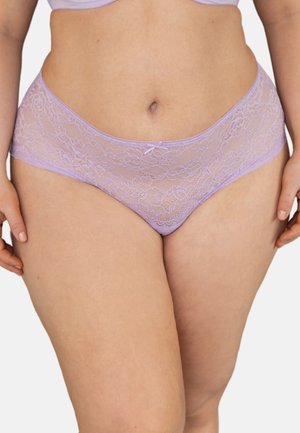 Frau trägt lavendelfarbene Spitzen-Hipster-Panties und passenden BH, zeigt den Mittelteil und die oberen Oberschenkel vor weißem Hintergrund.