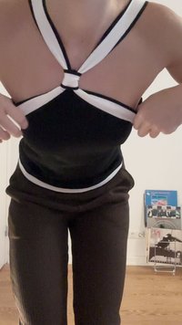 Black halter top with white accents, featuring a knotted back design. Paired with dark brown textured pants.