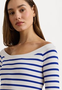 Baltas dryžuotas off-shoulder marškinėliai su mėlynomis horizontaliomis juostelėmis, turintis prigludusį dizainą ir lygų paviršių, pabrėžiantis iškirptę ir pečius.