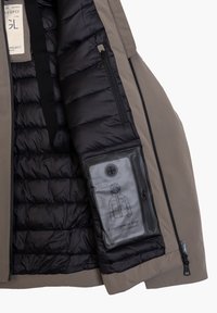 Giacca isolante con esterno grigio, interno trapuntato nero e una tasca con zip che presenta un'illustrazione della giacca e del testo.