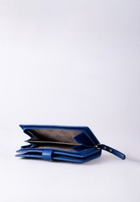 Blue leather wallet with a zip closure, multiple compartments, and a subtle interior pattern. Features a wrist strap for portability.