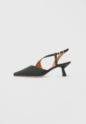 Pointed-toe slingback shoe in dark green woven material, featuring a slim black ankle strap and a low, chunky heel.