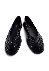 Zapatos negros tipo slip-on hechos de material trenzado, con tachuelas doradas, punta redondeada y suela lisa. Diseñados para comodidad y transpirabilidad.