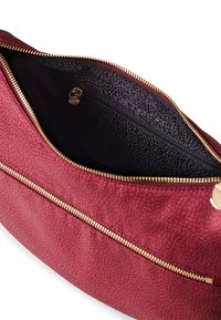 Red textured leather bag with gold hardware, featuring a zippered interior pocket and a smooth black lining.