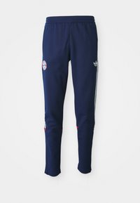 Σκούρο μπλε παντελόνι φόρμας από μαλακό υλικό. Διαθέτει λογότυπο, λευκές ρίγες κατά μήκος των πλαϊνών και κόκκινες λεπτομέρειες στις μανσέτες.