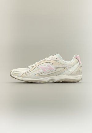 Sneaker New Balance bianca e rosa chiaro con dettagli in mesh e suede, mostrata di profilo su sfondo neutro.