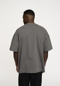 Grå oversized t-shirt med korte ærmer, rund hals og løs pasform, lavet af blødt bomuldsstof. Ensfarvet bagside uden logoer.
