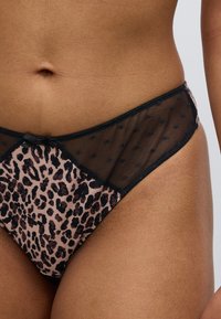 Κυλοτίνες με τύπωμα λεοπάρ, διακοσμημένες με διάφανο μαύρο δίχτυ και κεντρικό φιόγκο. Το ύφασμα έχει απαλή υφή με πουά σχέδια.