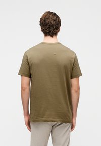 Ελιά πράσινο κοντομάνικο μπλουζάκι από μαλακό ύφασμα με στρογγυλή λαιμόκοψη. Απλός σχεδιασμός με ελάχιστες ραφές και λεπτομέρεια ραφής στους ώμους πίσω.