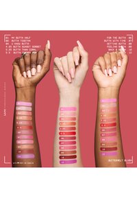 Trois bras levés avec des ongles peints montrent douze teintes de blush rose et corail testées du poignet au coude sur des peaux foncées, claires et moyennes.