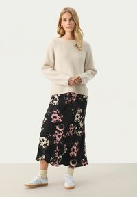 Cremefarvet ribbet sweater med rund hals, parret med en sort blomster midi skirt med pink og beige mønstre. Hvide sneakers fuldender looket.