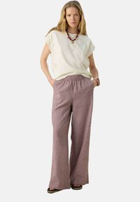 T-shirt en coton crème à coupe décontractée avec des manches courtes, associé à un pantalon large à motifs roses avec une taille élastique.