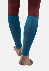 Compressiekousen in blauw en bordeauxrood, met getextureerde accenten en een nauwsluitende pasvorm, ontworpen voor actieve kleding met een gladde afwerking.