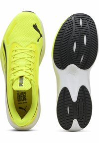 Scarpe da ginnastica di un brillante colore giallo con tomaia in rete, chiusura con lacci e dettagli neri. Presenta una suola in gomma texturizzata con un intersuola bianca.