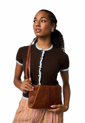 Top marrón de punto acanalado con ribete de volantes azul claro y botones, combinado con un bolso bandolera de cuero marrón con superficie texturizada.