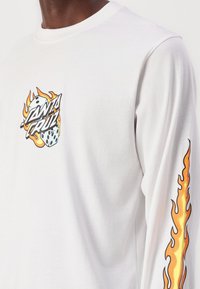 White long-sleeve shirt made of cotton, featuring a colorful "Santa Cruz" logo with dice and flame graphics on the chest and sleeve.